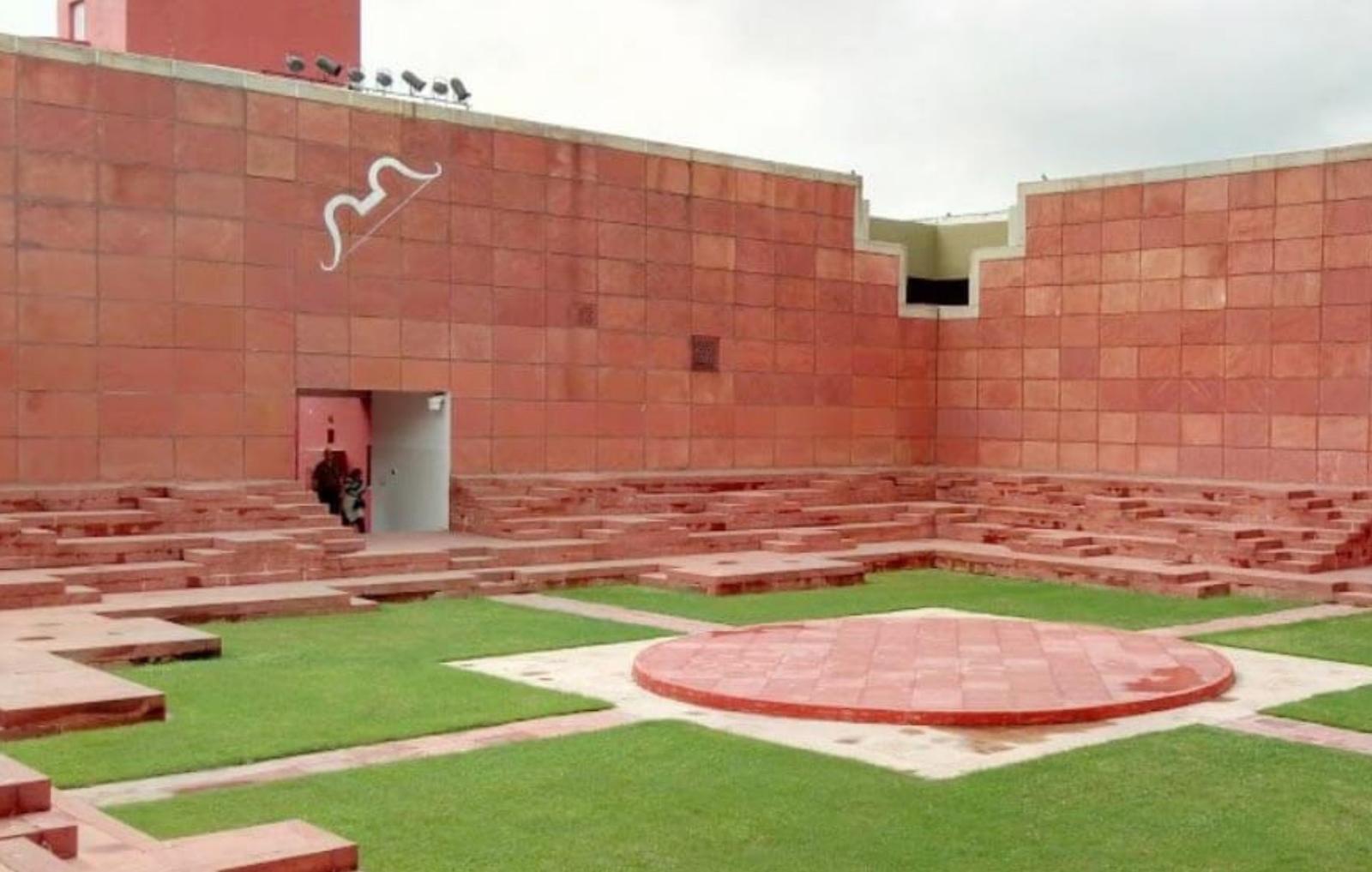 Photograph from the Journey thesis book: a stepped red-sandstone courtyard with tiered seating blocks and a circular red platform set into a grass parterre.